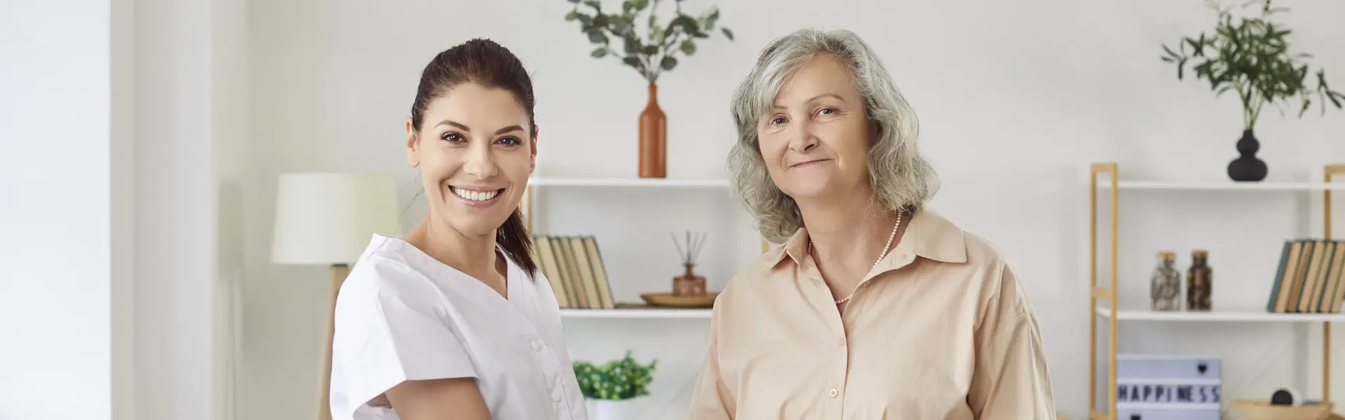 A female caregiver and an elderly woman smiling together