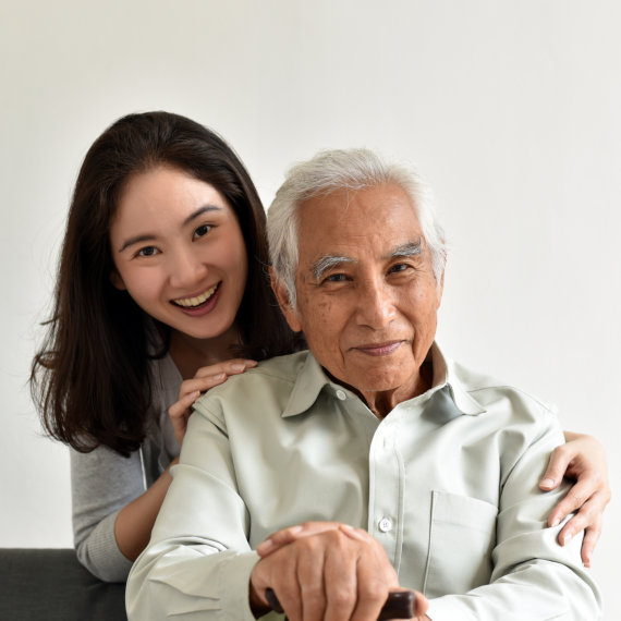 A female caregiver and an elderly man smiling together
