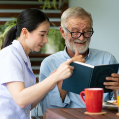 nurse and senior man reading book