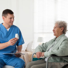 nurse man showing medicine bottle to senior woman