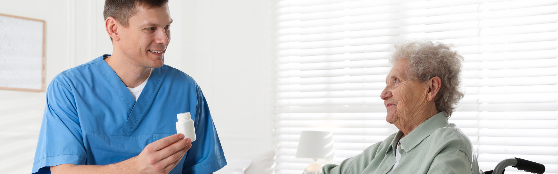 Caregiver giving medication to senior woman indoors. Home health