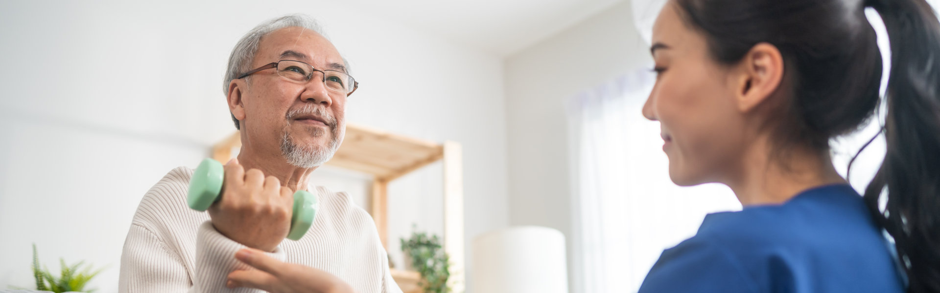 Asian older aged man doing physiotherapist with support from nurse.